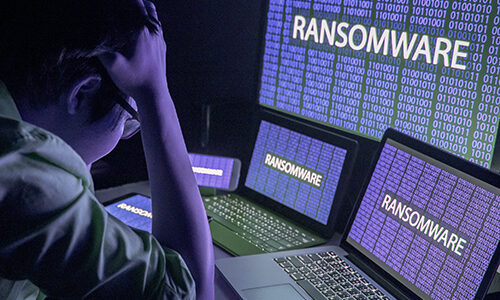 Young Asian male frustrated, confused and headache by ransomware attack on desktop screen, notebook and smartphone, cyber attack and internet security concepts